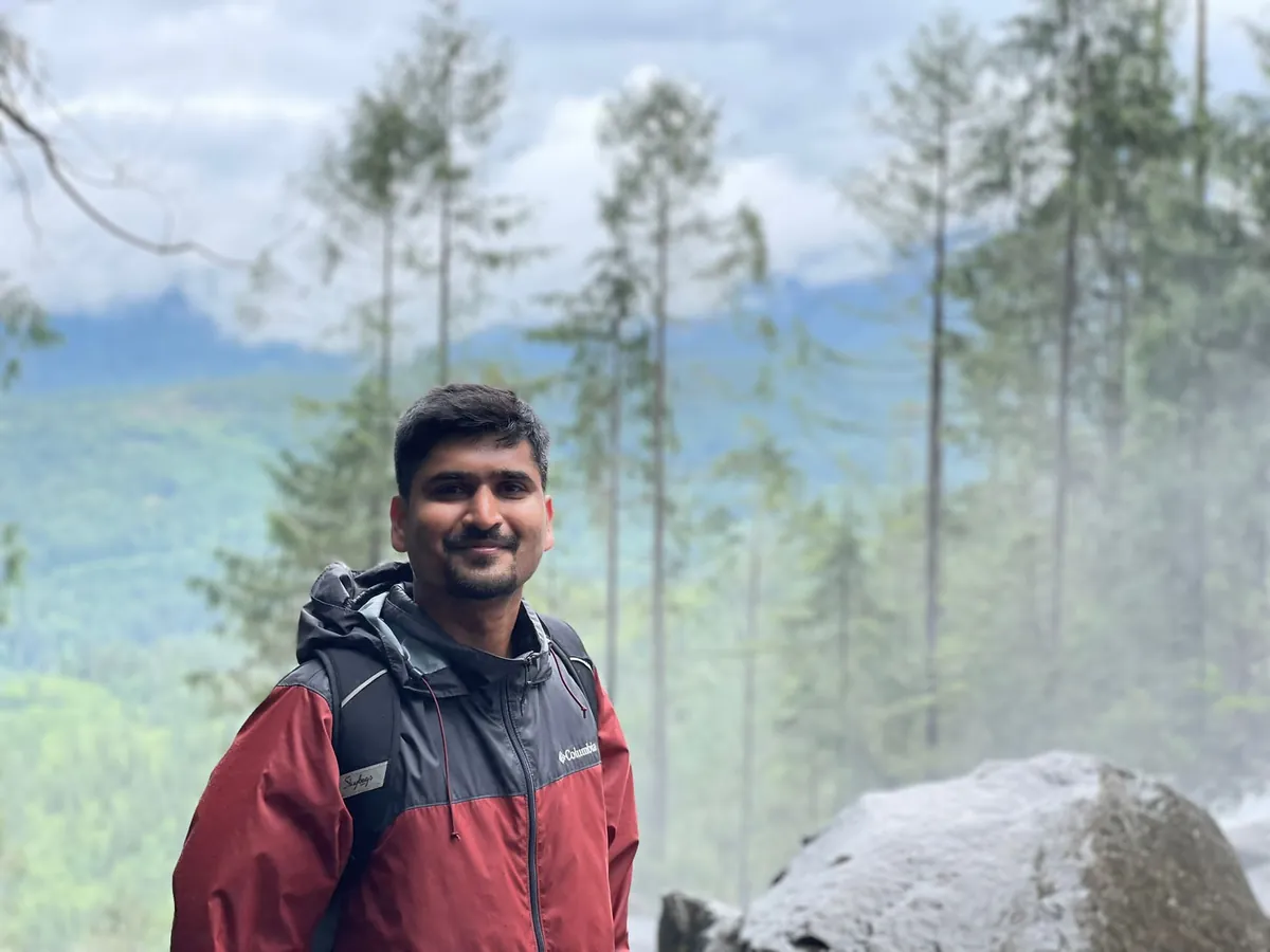 Abhi in a red rain jacket on a misty forest trail